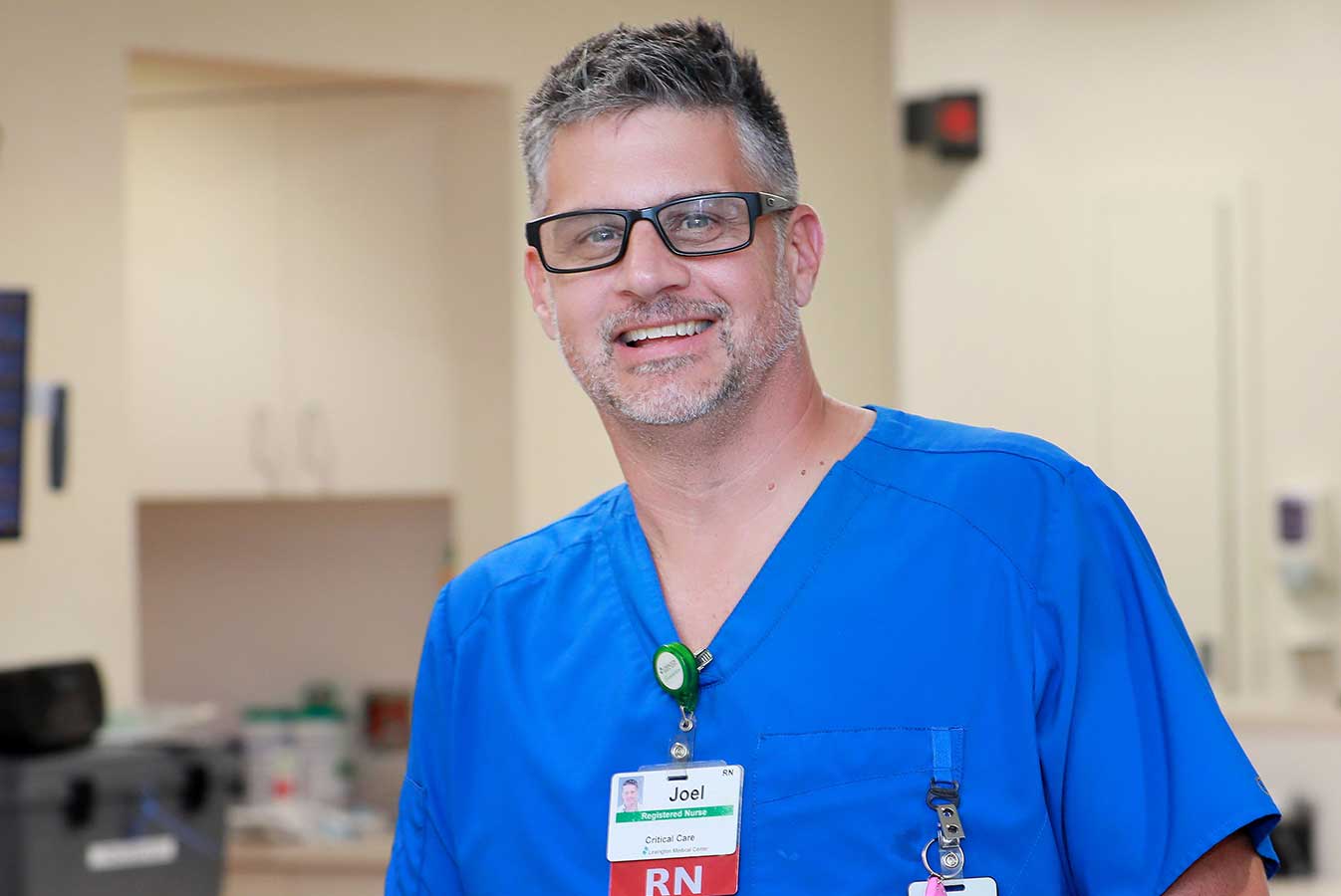 A smiling nurse wearing blue scrubs and a Lexington Health name tag.