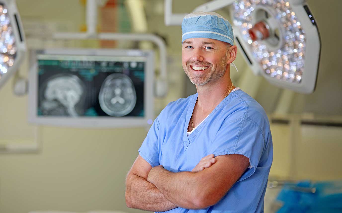 Physician smiling wearing blue scrubs.